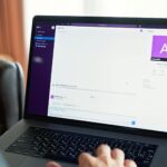 Person using a laptop with an online communication platform, showcasing modern work tech.