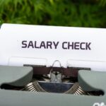 Close-up of a vintage typewriter typing 'Salary Check' on paper, symbolizing payroll and finance.