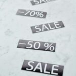Minimalist image showing sale signs with discount percentages on a marble surface.
