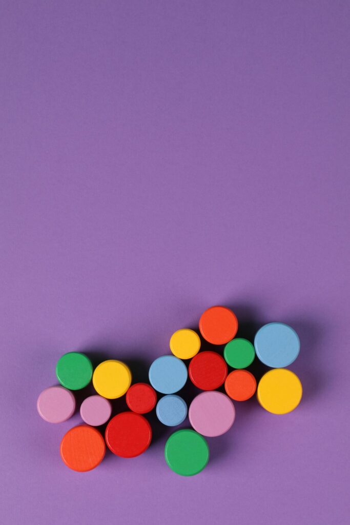 Vibrant wooden circles in various colors arranged on a purple background.