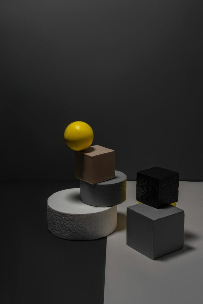 Abstract arrangement of geometric shapes including spheres and cubes on a dark gray background.