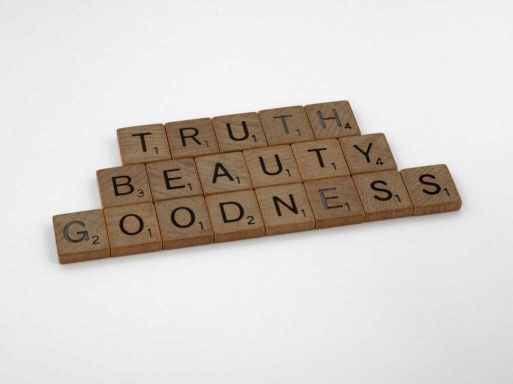 Wooden Scrabble pieces spell Truth, Beauty, Goodness on a white background.