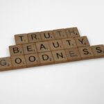 Wooden Scrabble pieces spell Truth, Beauty, Goodness on a white background.