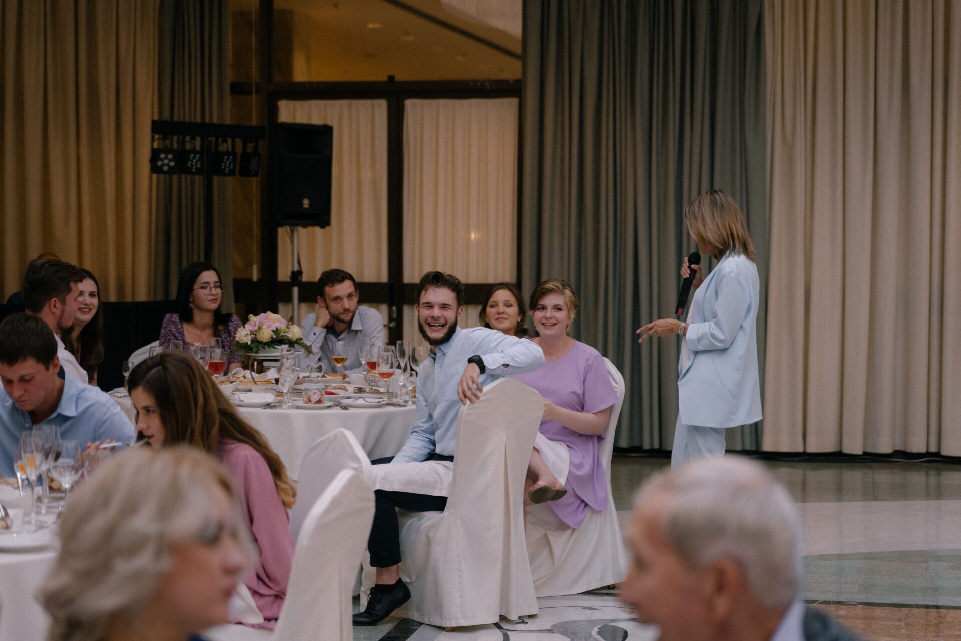 A lively wedding reception with guests enjoying food and conversation indoors.