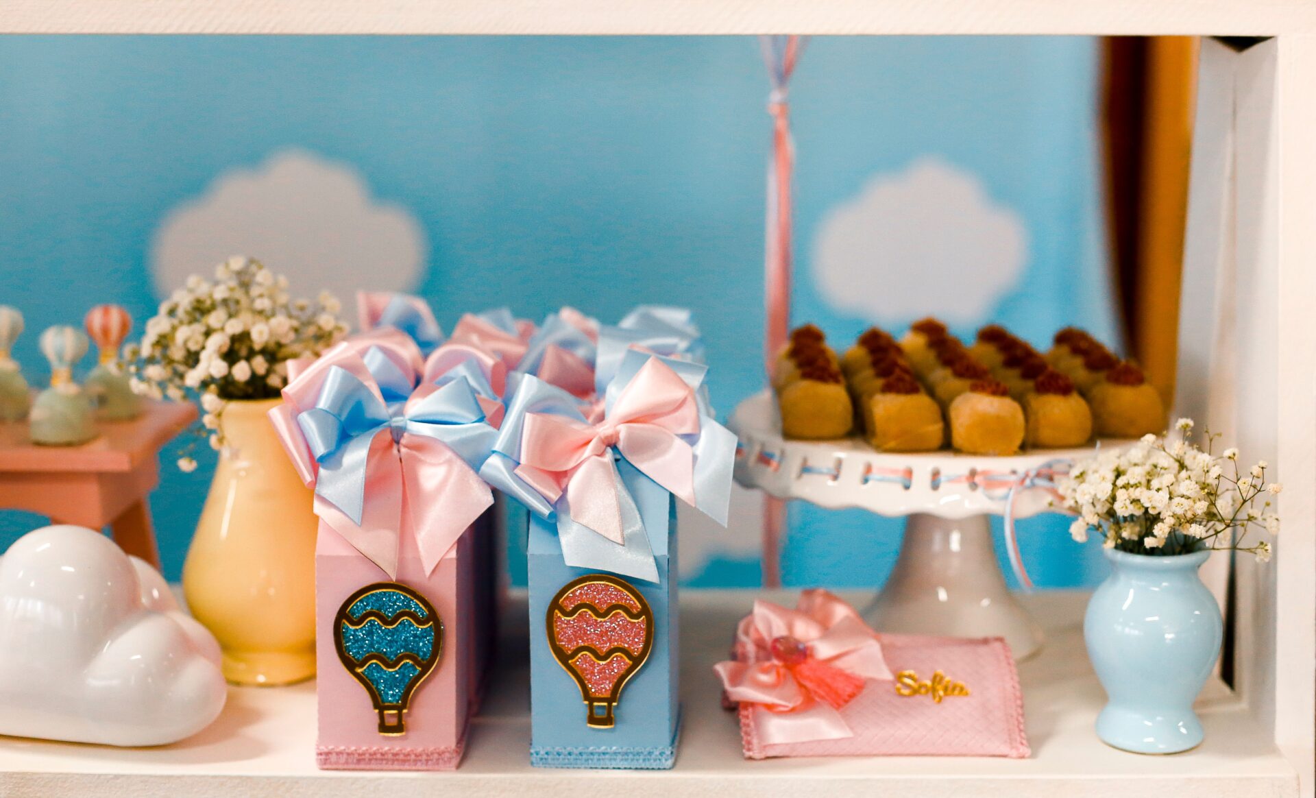BACKDROPS 3 Delightful baby shower setup with pastel gift boxes, treats, and floral accent in a whimsical cloud setting.