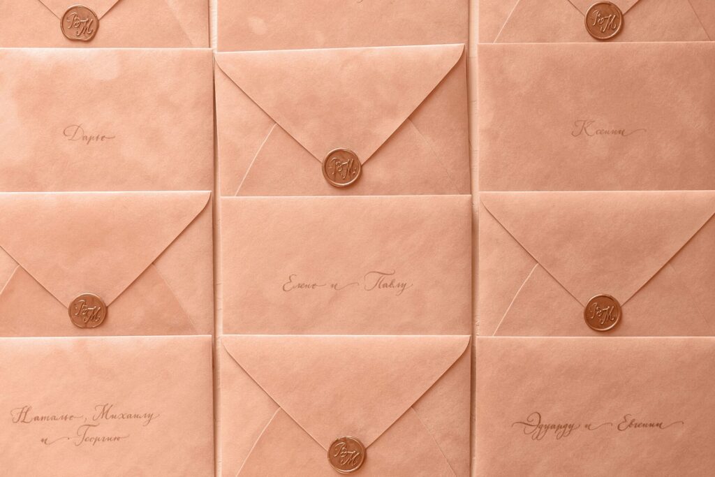 Rows of peach-colored envelopes sealed with wax, featuring elegant calligraphy.