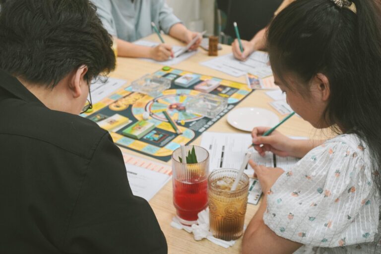 Group of adults playing a finance board game at a table. Engaging and educational activity.