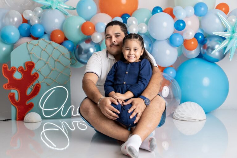 Father and daughter sitting amidst vibrant balloons, showcasing a joyful family moment.
