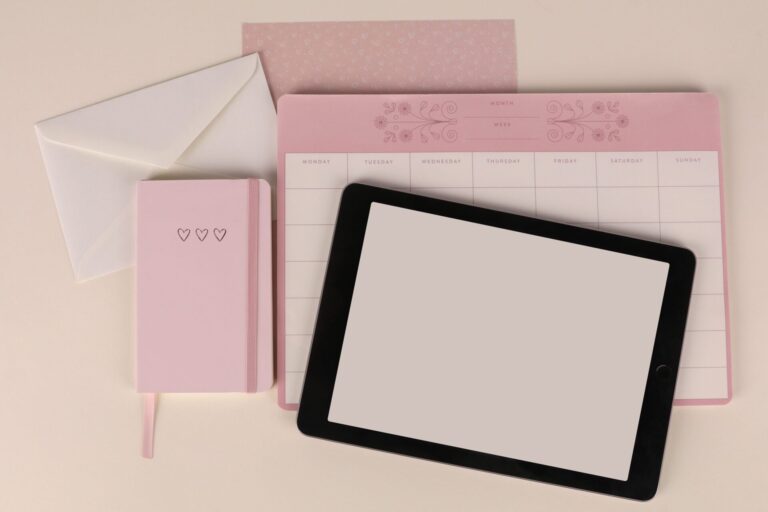 Flat lay of a pink planner, envelope, and tablet on a desk, perfect for organization themes.