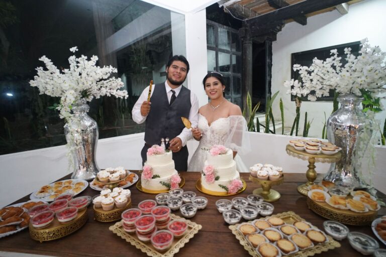 Bride and groom cutting cake at a joyful indoor wedding celebration.