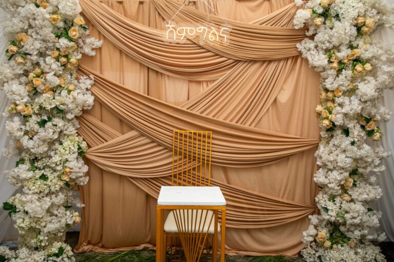 A beautifully decorated wedding backdrop featuring floral arrangements and draped fabric, ideal for elegant ceremonies.