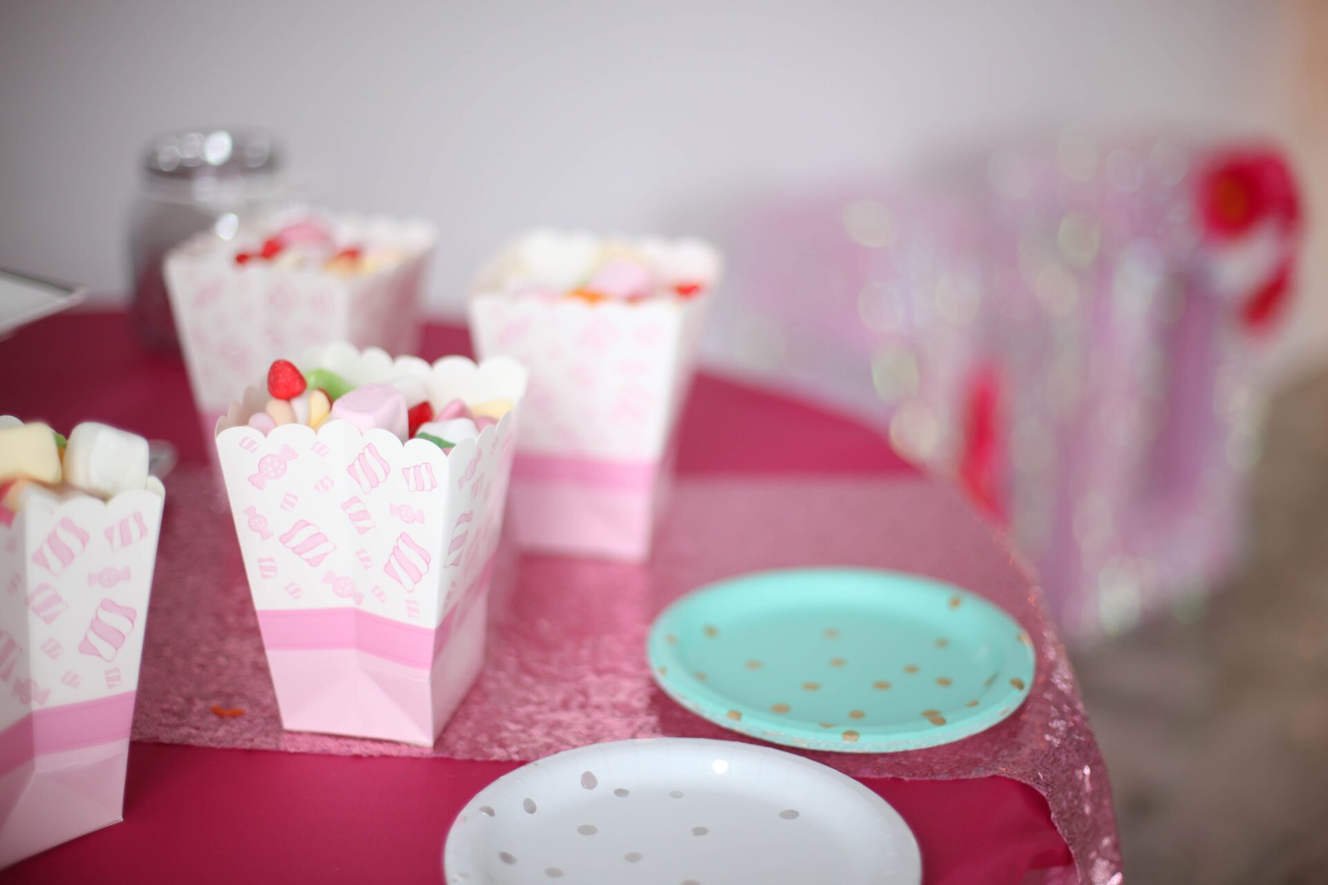 Disposable pink buckets filled with assortment of sweets and candies on party table