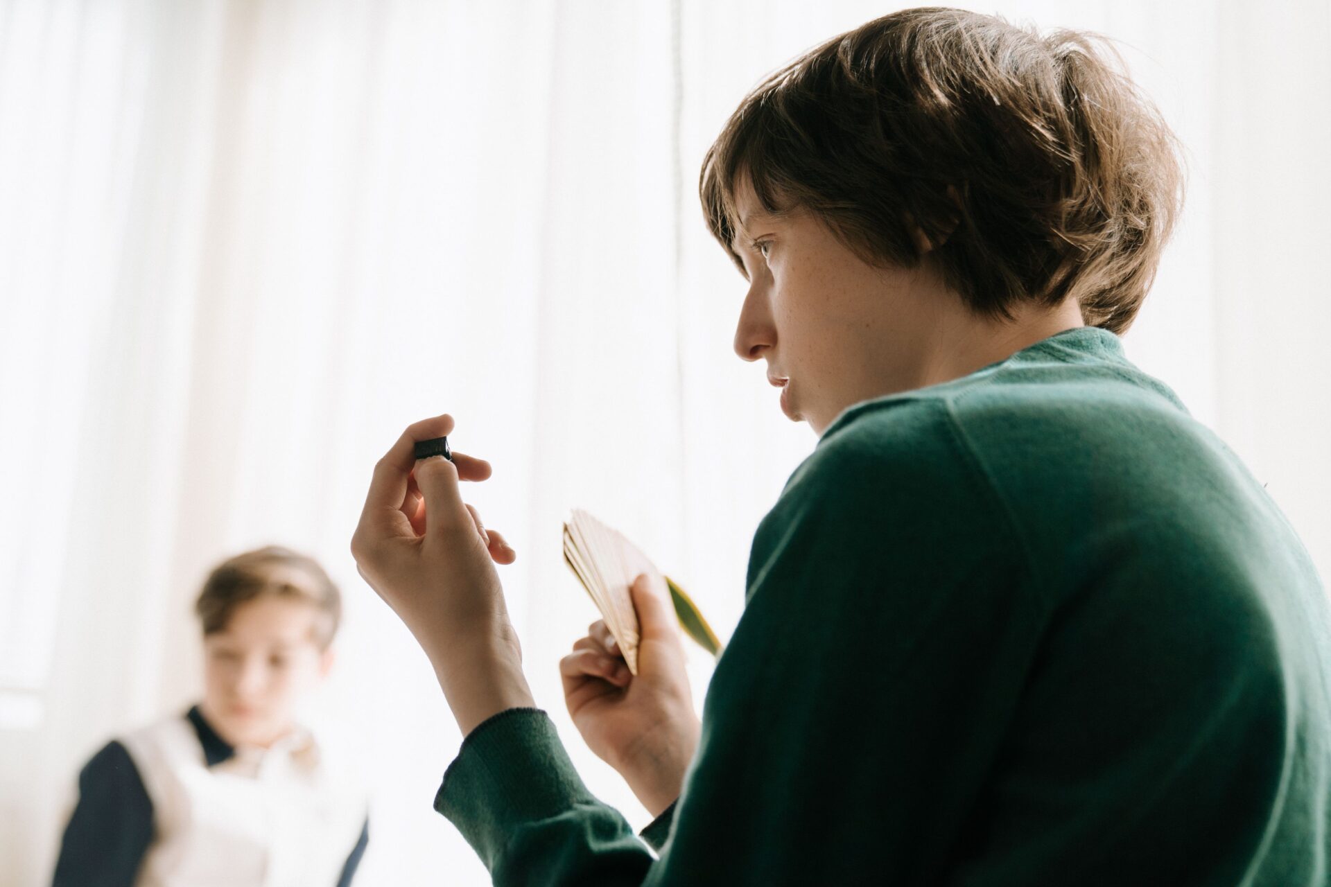 Two children playing a strategy card game indoors, focused and thoughtful.