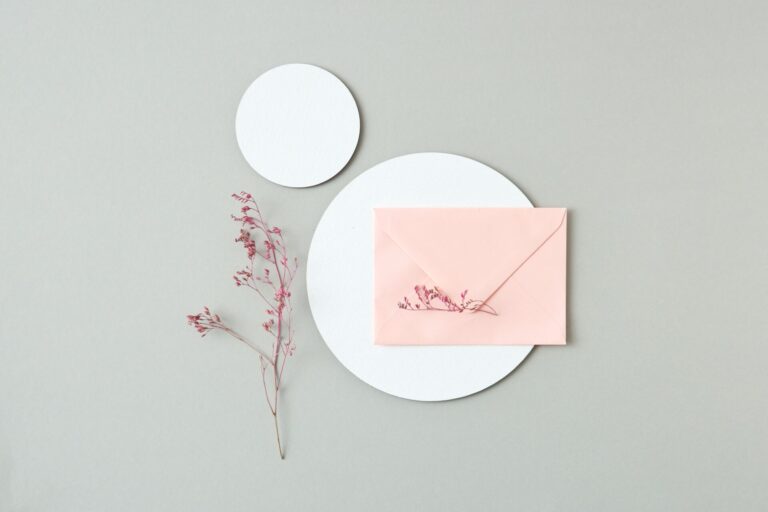 Top view of a pink envelope with floral accents on a minimalist background.