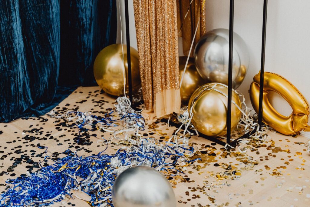 Festive indoor party scene with golden balloons, confetti, and decorations.