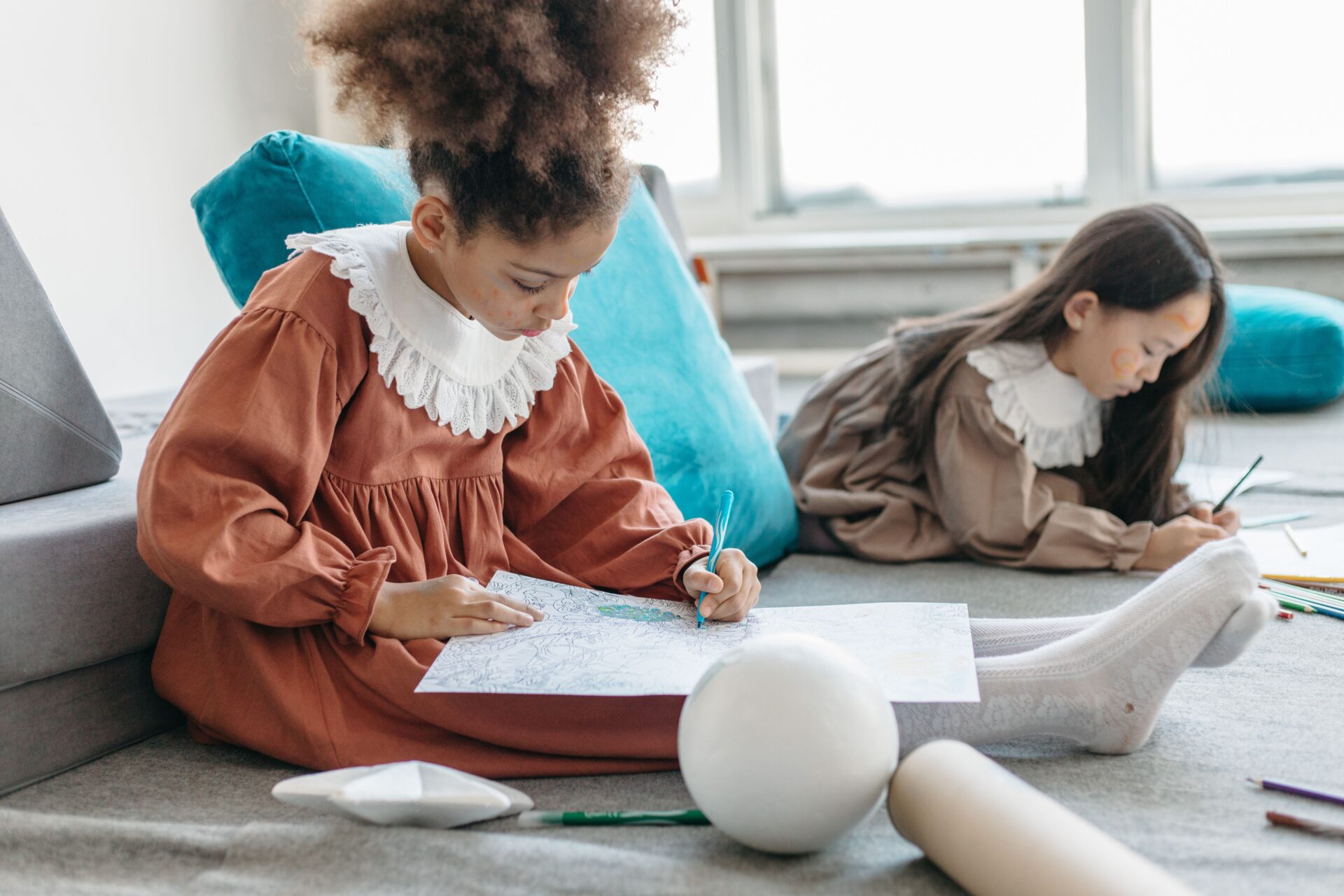 COLORING PAGES 4 Two girls enjoy drawing and coloring indoors, showcasing creativity and concentration.