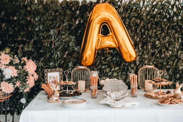 A beautifully arranged dessert table featuring a gold balloon, sweets, and floral decorations, perfect for celebratory events.