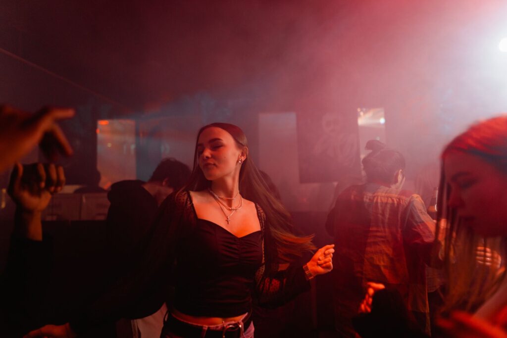Energetic party scene showing people dancing in a colorful nightclub atmosphere.