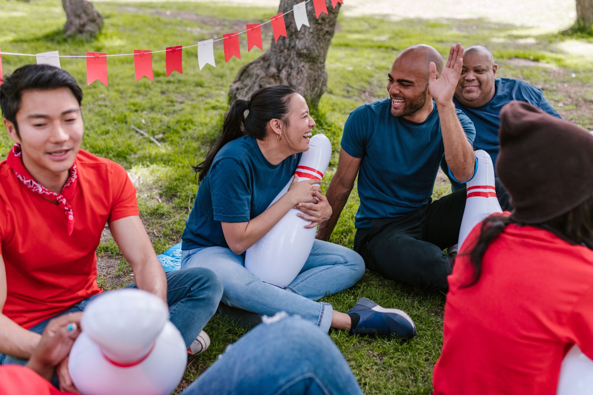 A multiracial group of adults enjoying outdoor team building activities with bowling pins.