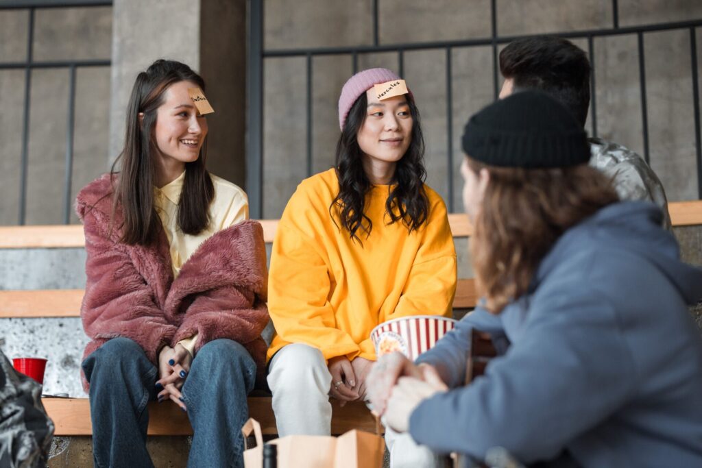 A diverse group of young friends playing a guessing game with sticky notes indoors.