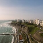 Stunning aerial view of Lima's coastline featuring cliffs and modern buildings by the Pacific Ocean.