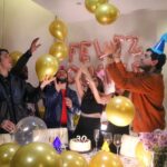 Vibrant birthday party with friends celebrating amidst balloons and festive decorations.