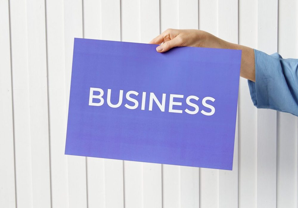 A hand holds a blue placard with 'Business' signage against a white background, ideal for startup themes.